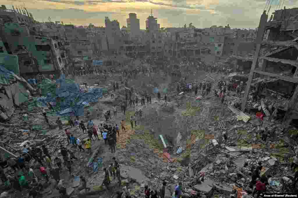 Palestinalylar 2023-nji ýylyň 31-nji oktýabrynda Gazanyň demirgazygyndaky Jabaliýa bosgun düşelgesindäki öýlere Ysraýyl tarapyndan edilen hüjüm ýerinde pidalary gözleýärler. (REUTERS / Anas al-Shareef)