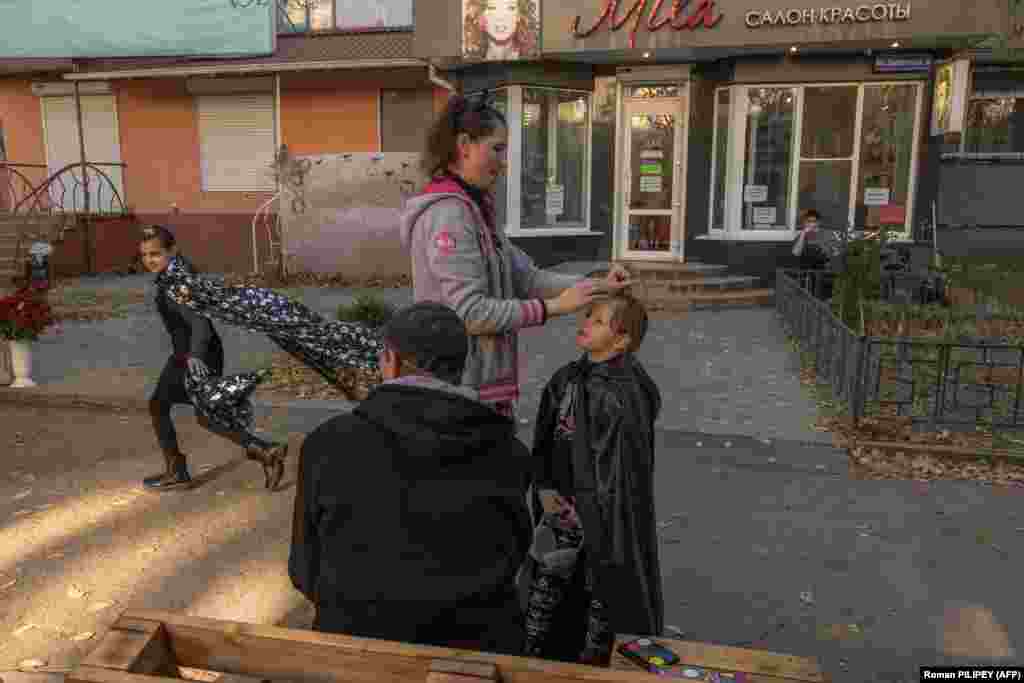 Марина допомагає своїй доньці Анні, 6 років, одягатися на Гелловін, а її чоловік Володимир спостерігає, як їхня донька Дарія бігає в чорній накидці, співаючи: «Я смерть, я ховаюся в тіні». «Ми святкуємо Гелловін, щоб забути війну», – сказав Володимир, усміхаючись сонячному світлу 