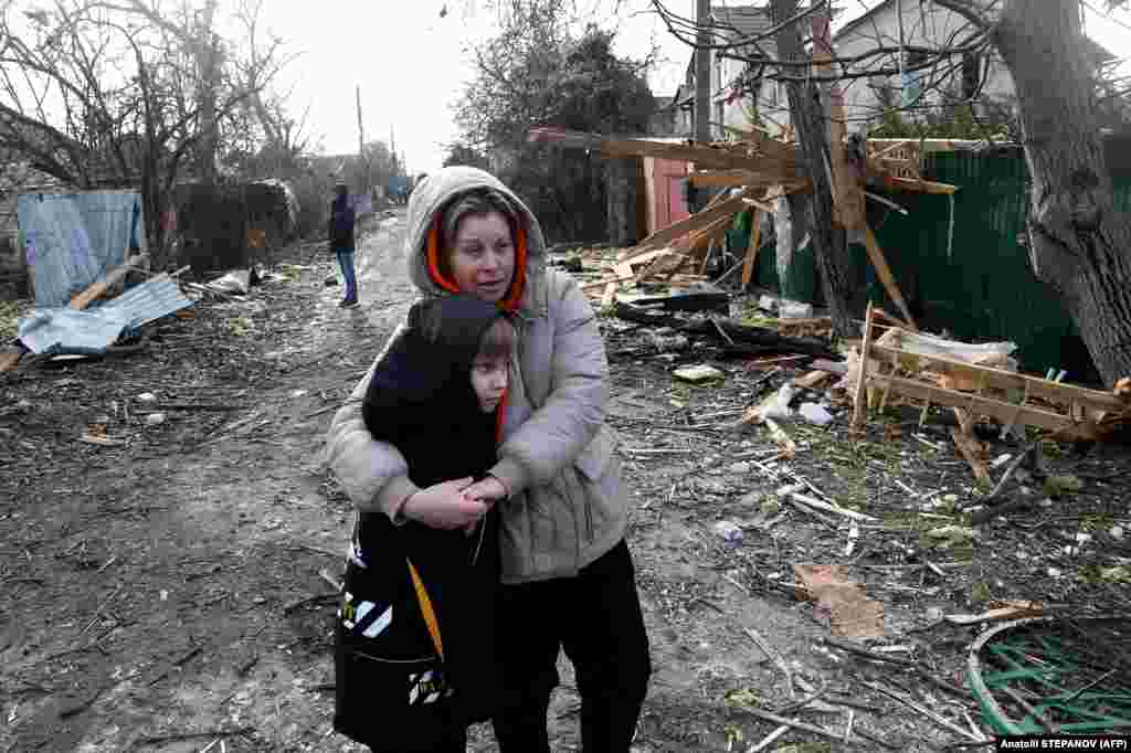 Locuitorii din zonă stau printre moloz, pe stradă, în fața unei case distruse ca urmare a unui atac cu drone în regiunea Odesa din Ucraina.
