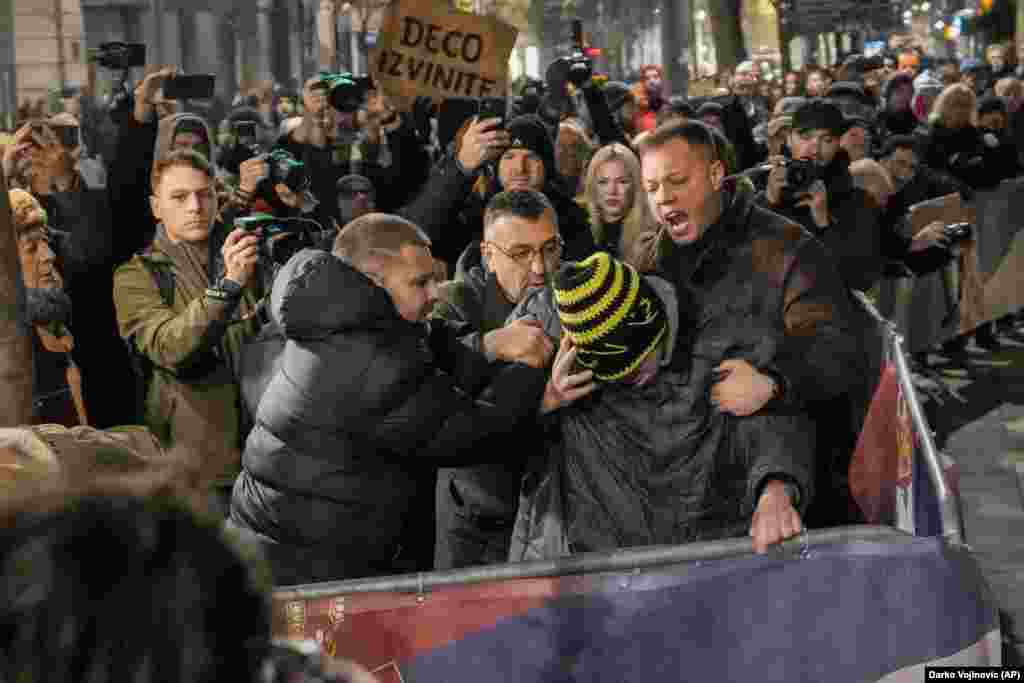 Un susținător al opoziției sârbe este reținut de colegii protestatari care încearcă să evite o escaladare violentă, în timpul unui protest la care s-au alăturat câteva mii de oameni în fața comisiei electorale de la Belgrad, pe 18 decembrie.