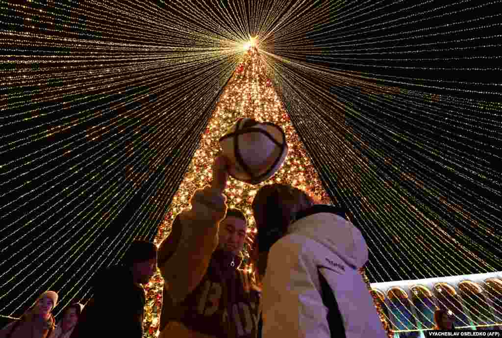 Oamenii se bucură de festivități în Piața centrală Ala-Too, decorată pentru a marca viitoarea sărbătoare de Anul Nou, în Bishkek, 20 decembrie.
