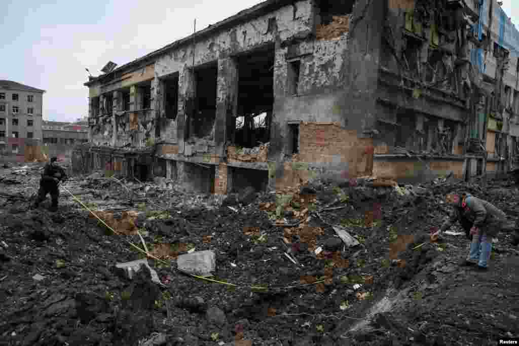 Експерти оглядають воронку від вибуху поруч із будівлею в центрі Харкова