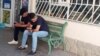 Türkmenistandaky dükanlaryň biriniň öňündäki oturgyçda oturyp, özleriniň mobil telefonlaryna seredýän ýaşlar (Illýustrasiýa suraty)