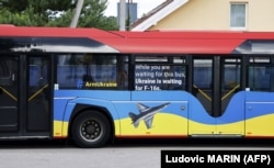 Натівський автобус з написами «Озброюйте Україну» та «Поки ви чекаєте на цей автобус, Україна чекає на F-16», припаркований біля місця проведення саміту НАТО у столиці Литви. Вільнюсі 11 липня 2023 року