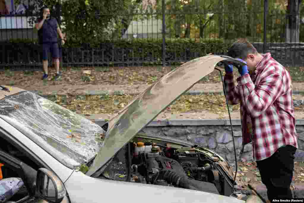 Киянин оглядає свій автомобіль, який постраждав під час ракетного обстрілу, 21 вересня 2023 року