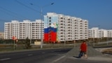 Женщина идет мимо недавно построенных домов в Мариуполе. Местные жители говорят, что новое жилье преимущественно отдают под ипотеку приезжим россиянам