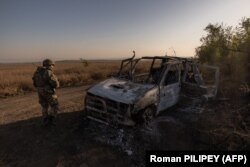 Військовослужбовець 65-ї механізованої бригади ЗСУ проходить повз знищену машину біля окопів, побудованих військами РФ, біля Роботиного у Запорізькій області, 1 жовтня 2023 року. ЗСУ звільнили Роботине наприкінці серпня під час контрнаступу