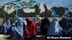 Owgan aýallary saud arabystanly ýardam topary tarapyndan paýlanýan azyklyk bukjalary kabul edip alýarlar. Aprel, 2022 ý. Kabul, Owganystan.