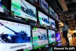 Женщина стоит перед экранами телевизоров, транслирующих новости о российских войсках, начавших наступление на Украину. Гонконг, 24 февраля 2022 года