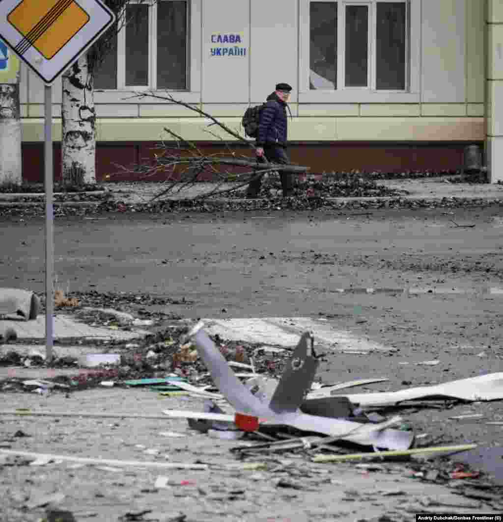 Чоловік несе гілки дерева, які використає на дрова. На стіні за ним графіті з написом «Слава Україні!» Андрій Дубчак каже, що жителі залишаються у місті з різних причин, враховуючи бажання захистити своє майно та страх перед тим, яким буде життя внутрішньо переміщеної особи. Деякі мирні жителі, за його словами, чекають приходу обіцяного кремлівською пропагандою «русского мира»