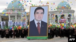 Adamlar Türkmenistanyň prezidenti Gurbanguly Berdimuhamedowyň äpet portretini göterip barýarlar.