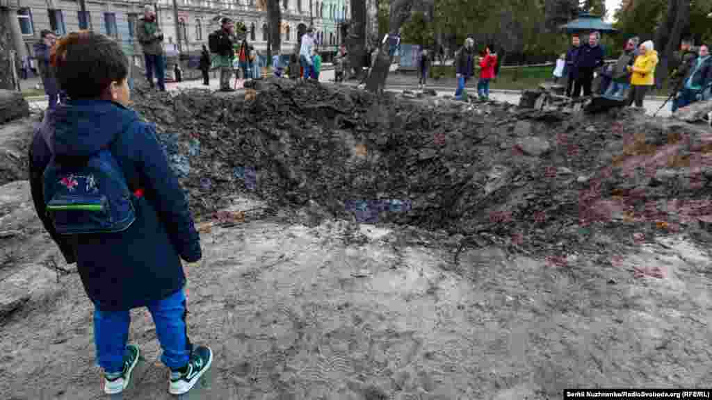 Хлопчик дивиться на вирву від ракетного удару на дитячому майданчику у парку імені Тараса Шевченка