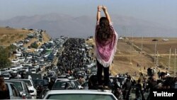 دختری پشت سر شرکتکنندگان در مراسم چهلم مهسا امینی در شهر سقز