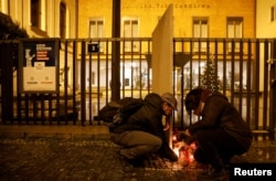 People light candles in front of the main building of Charles University following the mass shooting.