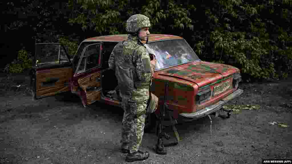 Український військовий біля старої моделі автомобіля радянського виробництва «Жигулі». Десь біля Лисичанська. Донбас. 23 травня 2022 року 