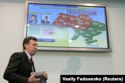 Голова Центральної виборчої комісії України Сергій Ківалов проходить повз екран з попередніми результатами другого туру президентських виборів. 22 листопада 2004 року