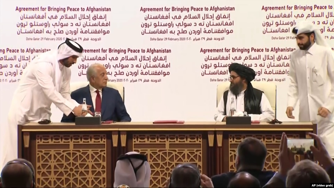 Semnarea acordului între SUA și talibani pentgru încetarea războiului din Afganistan, Doha, 29 februarie 2020. În stânga, reprezentantul special al SUA  Zalmay Khalilzad, liderul talibanilor Mullah Abdul Ghani Baradar (dreapta)