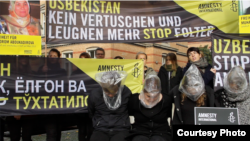 Amnesty International уюму кыйноолорду токтотуу талабы менен Өзбекстандын Берлиндеги элчиканасынын жанында уюштурган акция. 2014-жыл, октябрь.