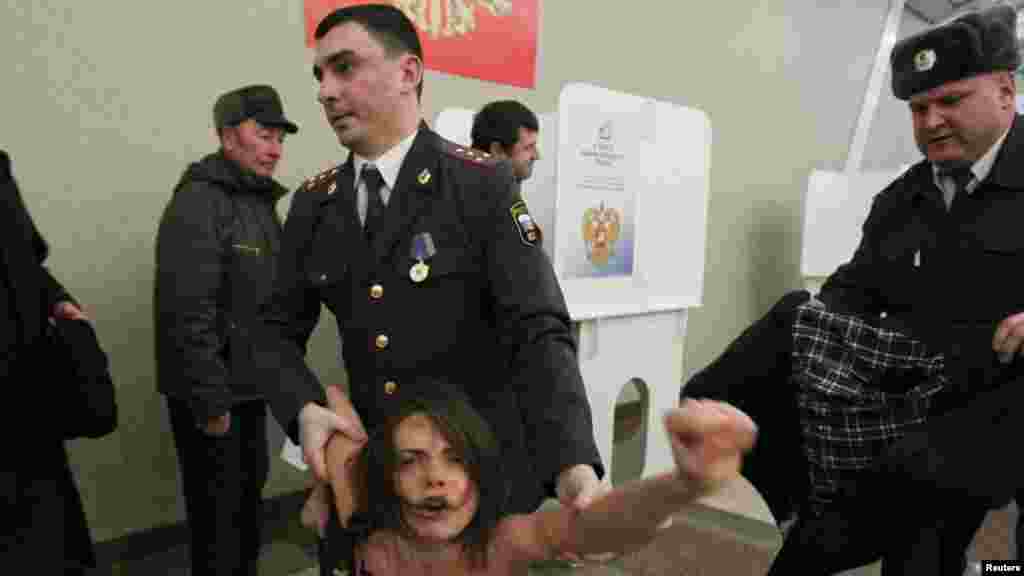 A feminist activist from the FEMEN group is arrested while trying to steal the ballot box used by Prime Minister Vladmir Putin as part of an antigovernment protest.