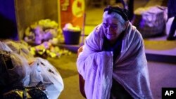 O femeie de etnie armeană din Nagorno-Karabah se încălzește lângă o tabără de corturi, după ce a sosit în orașul armean Goris, 29 septembrie