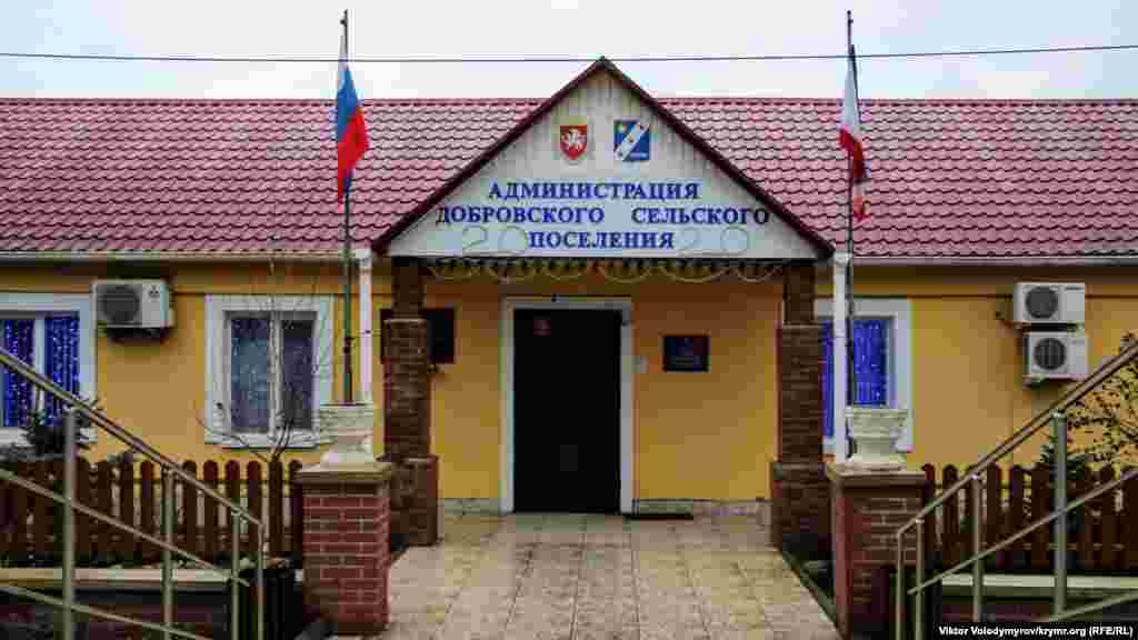 Навпроти розташована підконтрольна Росії адміністрація Добровського сільського поселення. Цифри на козирку і гірлянди у вікнах – спроба співробітників установи створити новорічну атмосферу