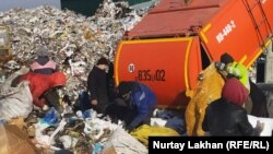 Большие и малые грузовики въезжают по очереди и выгружают мусор. Несколько человек следят за поступающим мусором. Алматы, 4 декабря 2020 года.
