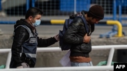 Türkiýe. Saklanan migranty alyp barýan polisiýa ofiseri.