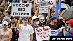 Люди тримають плакати з написами: «Хай живе Білорусь, Лукашенко вбивця», «Росія без Путіна» та «Я, ми, Сергій Фургал, зупиніть репресії мітингувальників» під час несанкціонованої акції протесту в Хабаровську, Росія. 15 серпня 2020 року
