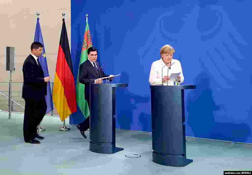 Germaniýanyň kasnleri Angela Merkel (s) we Türkmenistanyň prezidenti G.Berdimuhamedow (ç) metbugat-konferensiýasynda çykyş etmek üçin öz münberlerine barýarlar, Berlin, 29-njy awgust, 2016. 