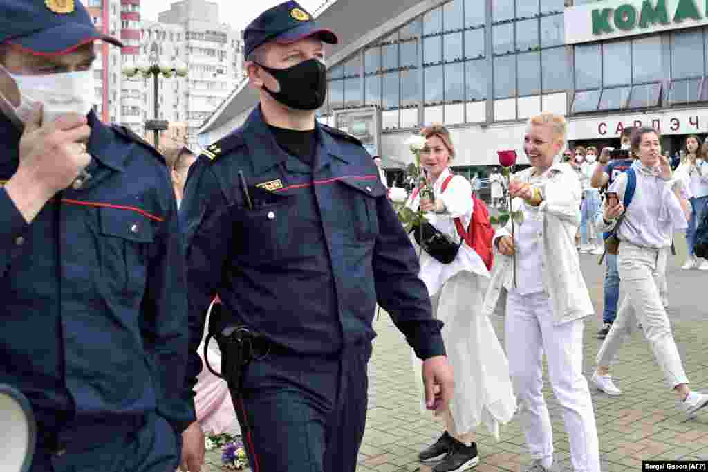 Антиурядові протестувальники дарують квіти двом працівникам міліції у Мінську, 12 серпня