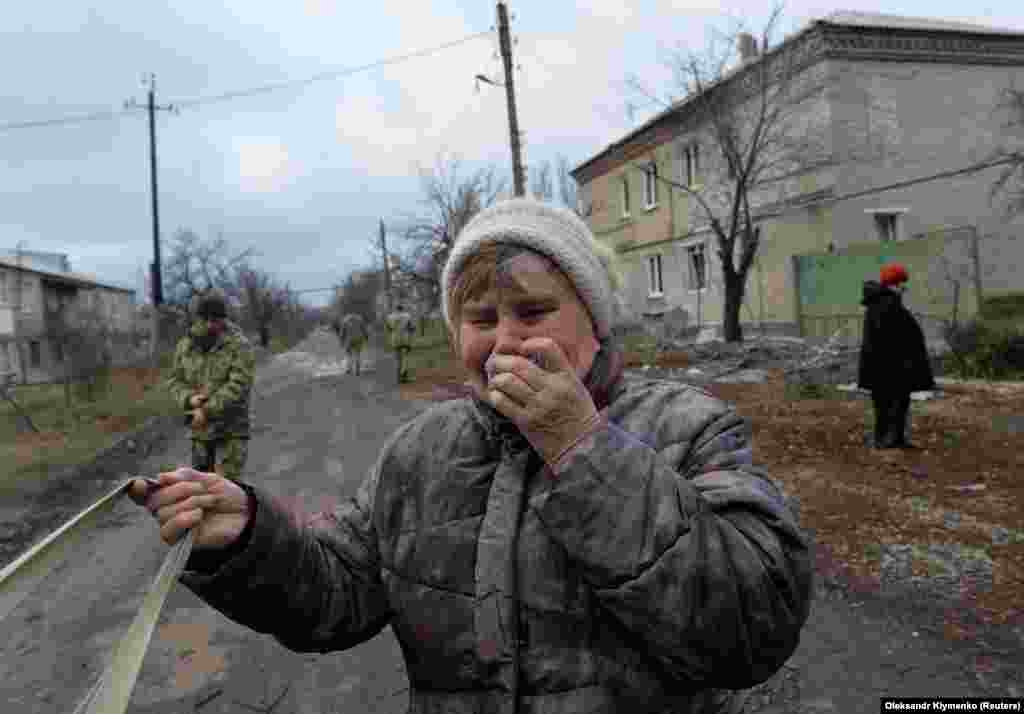 Жінка плаче біля свого будинку, який був пошкоджений під час обстрілу, здійсненого російськими гібридними силами з реактивної системи залпового вогню «Град» по населеному пункту Новолуганське на Донеччині, 19 грудня 2017 року