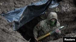 Український військовослужбовець тримає артилерійський снаряд, готуючись вистрілити з гаубиці в бік російських військ, 4 березня 2024 року