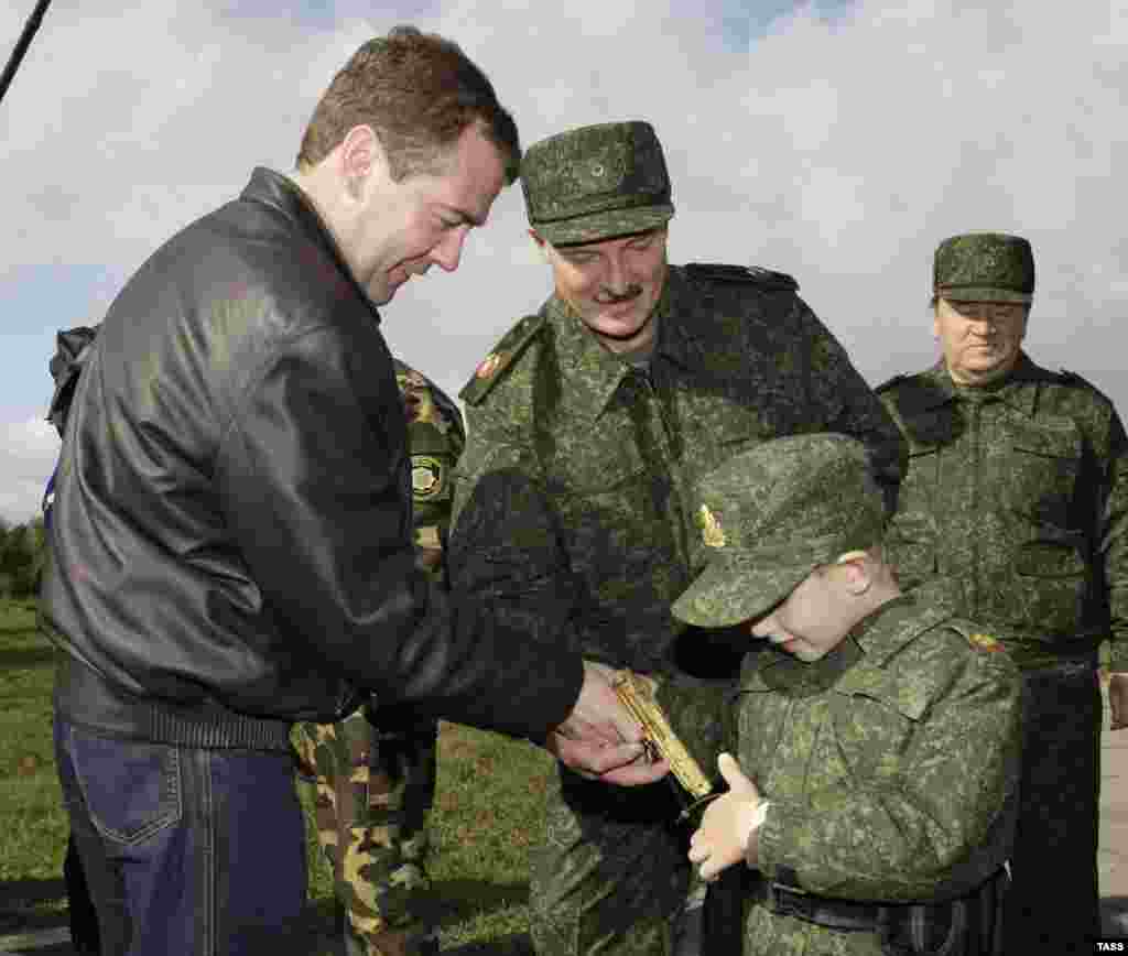 Президент Росії Дмитро Медведєв (ліворуч), його білоруський колега Олександр Лукашенко і п’ятирічний син президента Білорусі Микола, 2009 рік. Хлопчик кладе в кобуру золотий пістолет, подарунок Медведєва