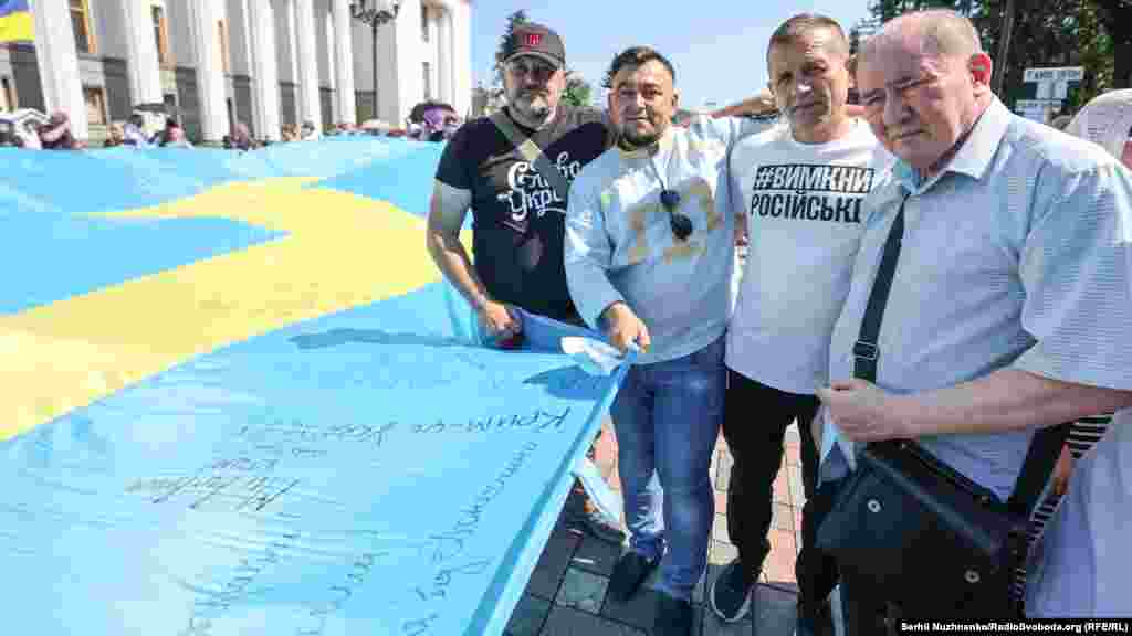 Кримчани, серед яких Ільмі Умеров та Володимир Балух (обидва справа), несуть кримськотатарський прапор до будівлі Верховної Ради України, 15 липня 2021 року