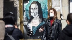Туристка в Барселоні позує для фото поруч із графіті, на якому зображена Мона Ліза в масці під назвою «Вірус мінливого світу». Іспанія. Весна 2020 року