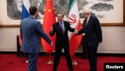 Chinese Foreign Minister Wang Yi welcomes Russian Deputy Foreign Minister Sergey Ryabkov and Iranian Deputy Foreign Minister Kazem Gharibabadi, before a meeting regarding the Iranian nuclear issue at Diaoyutai State Guest House on March 14, 2025, in Beijing, China