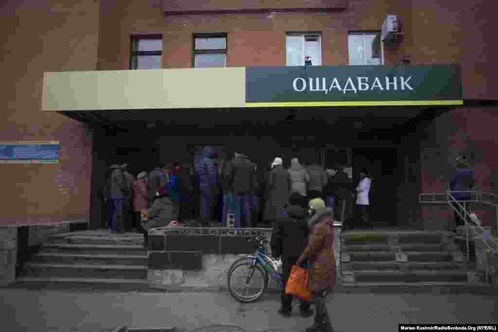 Зі сторони під контролем угруповання «ЛНР» на контрольовану Україною територію люди прямують за пенсіями та дешевшими продуктами. На фото – черга до банкомату «Сбербанку» у центрі Станиці Луганської. За словами місцевої жительки, зранку тут збирається черга до тисячі людей