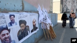 Əfqan qadınlar Kabildə Taliban liderlərinin posterlərinin və bayraqlarının yanından keçirlər.