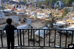 Палестинский ребенок смотрит на могилы людей, погибших в результате израильской бомбардировки сектора Газа и похороненных на территории больницы «Аль-Шифа» в городе Газа. 31 декабря 2023 года.