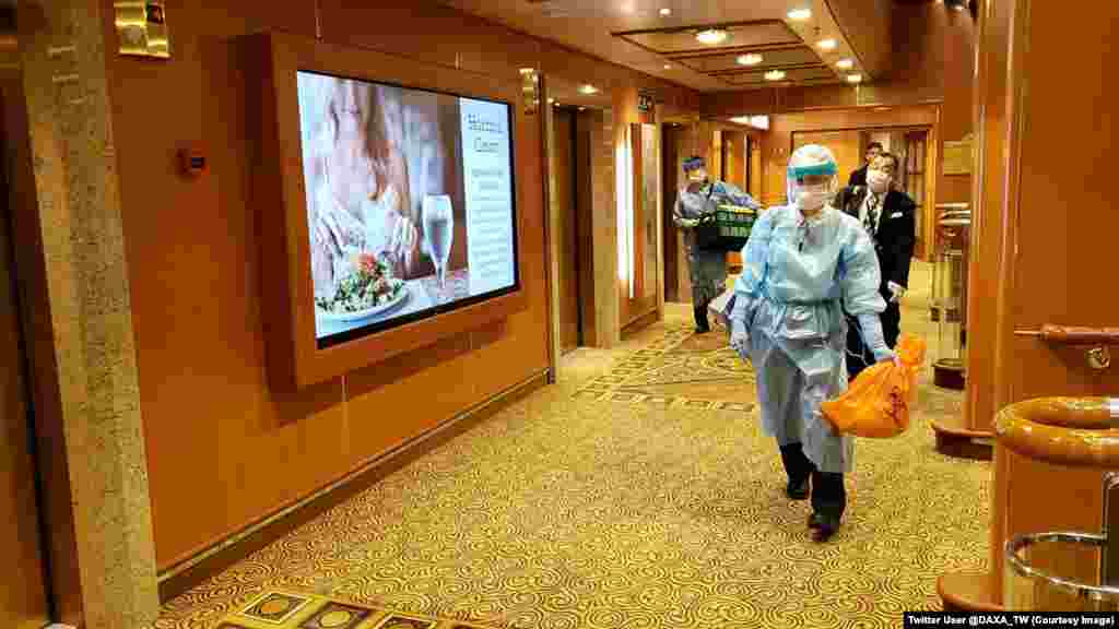 «Diamond Princess» саякат кемесинин ичинде коргонуучу кийимчен бара жаткан киши. Кеме вирустун айынан 3-февралда Жапониянын жээгине келгенден бери карантинде турат. 