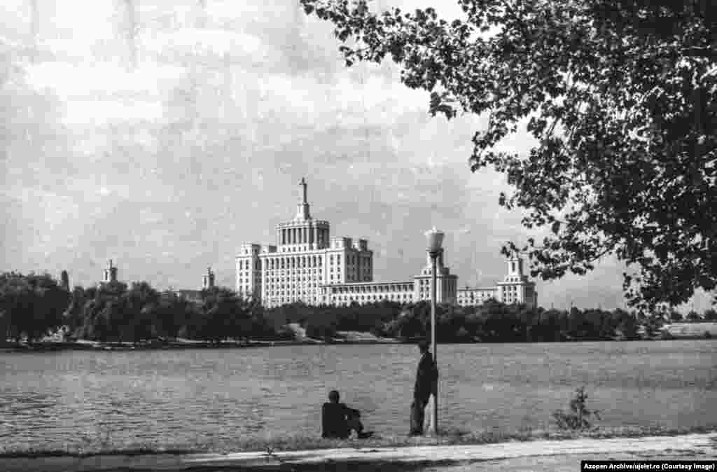 Чоловіки дивляться на озеро Герастрау в Бухаресті у бік будинку, що мав назву «Іскра», де в Румунії часів Чаушеску розміщувалася редакція державної комуністичної газети. На той час це був найвищий хмарочос у Бухаресті заввишки 104 метри. Зараз ця будівля називається «Будинок вільної преси»