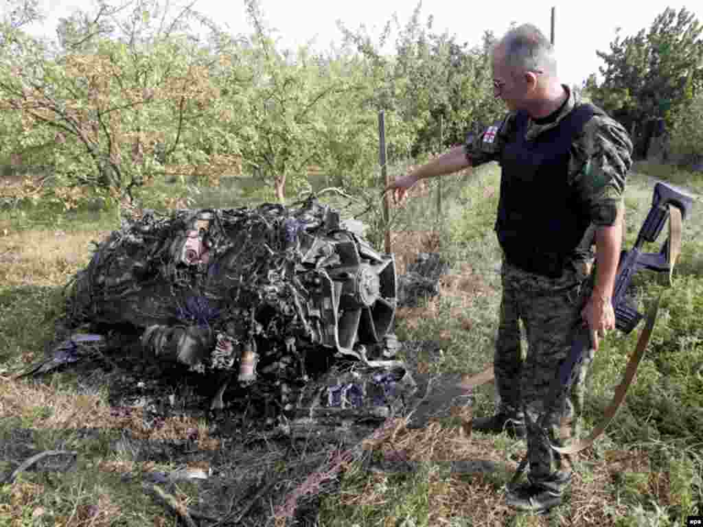 Грузинський солдат над збитим російським бомбардувальником біля села Дзевера, 9 серпня - epa01437207 A Georgian military serviceman stands at the remains of a Russian bomber, downed by Georgian forces near the village of Dzevera some 100km from Tbilisi, Georgia 09 August 2008. Georgia claims that 10 Russian warplanes were downed during the past two days. EPA/DAVID MDZINARISHVILI / POOL
