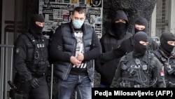 Српските полицајци го придружуваат водачот на навивачите на Партизан, Вељко Беливук (2Л) за време на рацијата на стадионот на Партизан во Белград, 4 февруари 2021 година